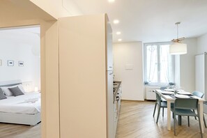A modern bedroom with a bed, a dining area with a table and chairs, and a kitchen area with cabinets. - Quarda, Apartment in Savona Old Town (Savona)