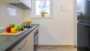 Una cocina moderna con ventana, estufa y tabla de cortar con verduras.