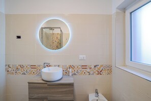 Ein Badezimmer mit rundem Spiegel, Waschbecken und Toilette.
