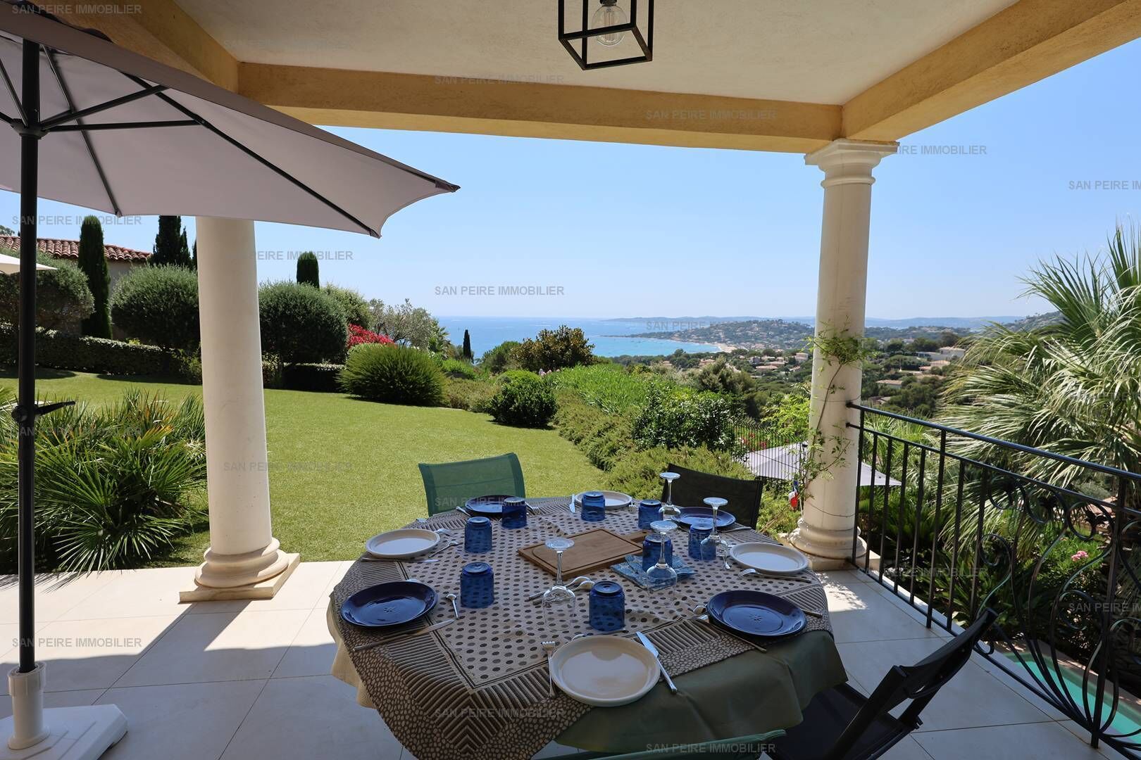 A covered outdoor dining area with a table set for four, overlooking a scenic view.