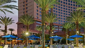 A hotel pool area with sun loungers and palm trees, surrounded by a high-rise building. - 2-bedroom suite in lovely Club Wyndham Desert Blue in Las Vegas During Formula 1 (Las Vegas)