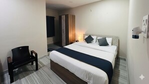 Una habitación de hotel con dos camas, un escritorio, una silla y un armario.
