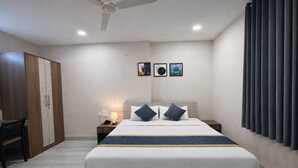 Una habitación de hotel con cama, mesita de noche, lámpara y armario.