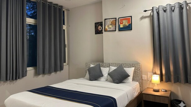 Una cama bien hecha con un detalle en azul, una lámpara de noche y una mesita de noche.