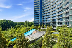 Ein Hochhaus-Hotel mit Schwimmbad, umgeben von üppigem Grün.