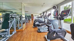 Uma academia com equipamentos de cardio, aparelhos de musculação e um espelho grande.
