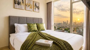 Quarto de hotel moderno com uma cama grande, vista para a cidade e obras de arte na parede.