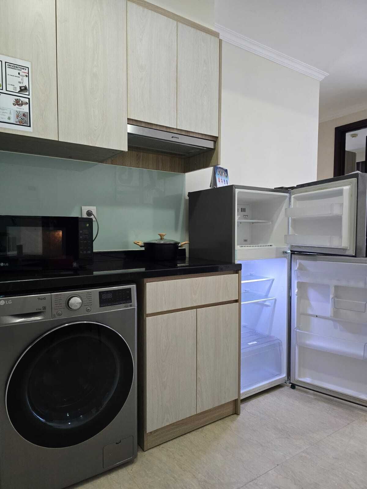 A compact kitchen with a washing machine, a microwave, and a refrigerator.