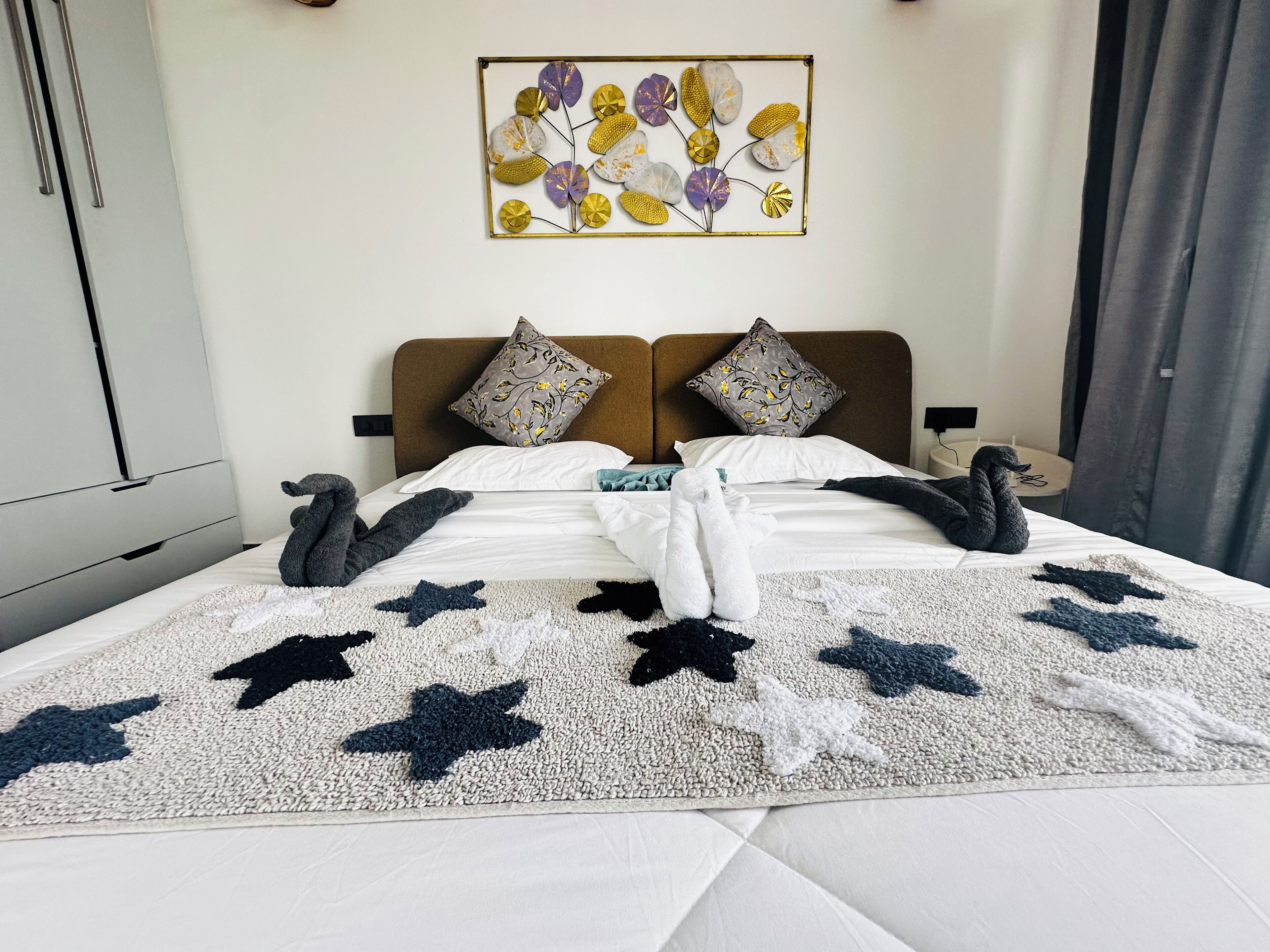 A neatly made bed with a star-patterned throw, two pillows, and a decorative wall piece above.
