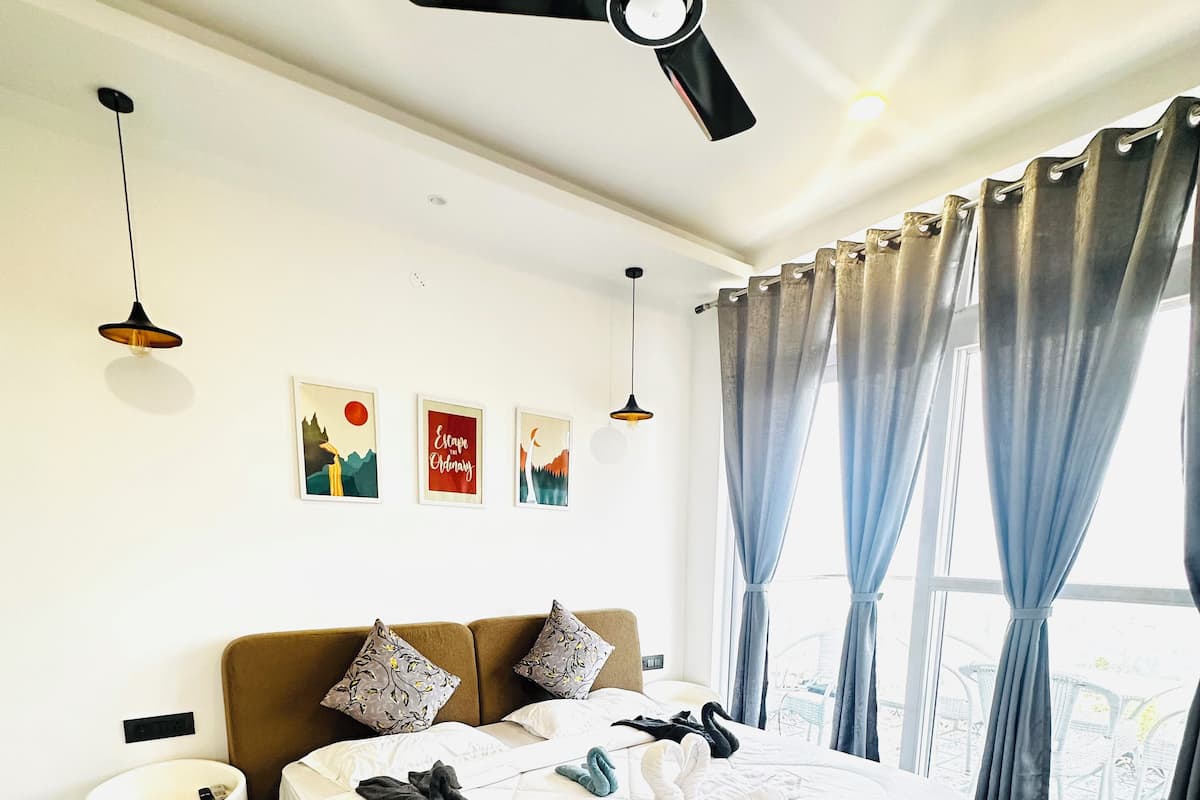 A modern bedroom with a large bed, a ceiling fan, and artwork on the wall.