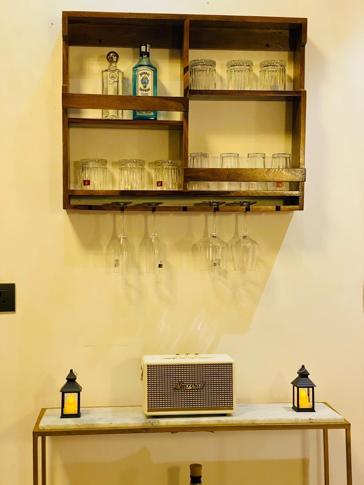 A wall-mounted shelf with bottles, glasses, and a radio.