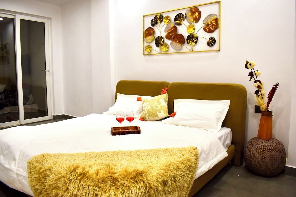 A hotel room with a bed, a large window, and a wall-mounted artwork.