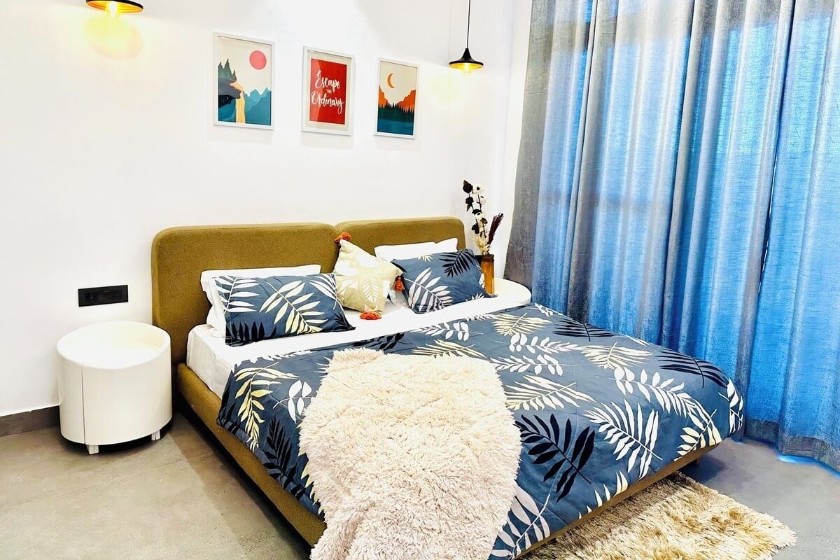 A modern bedroom with a bed, bedside tables, and wall art.