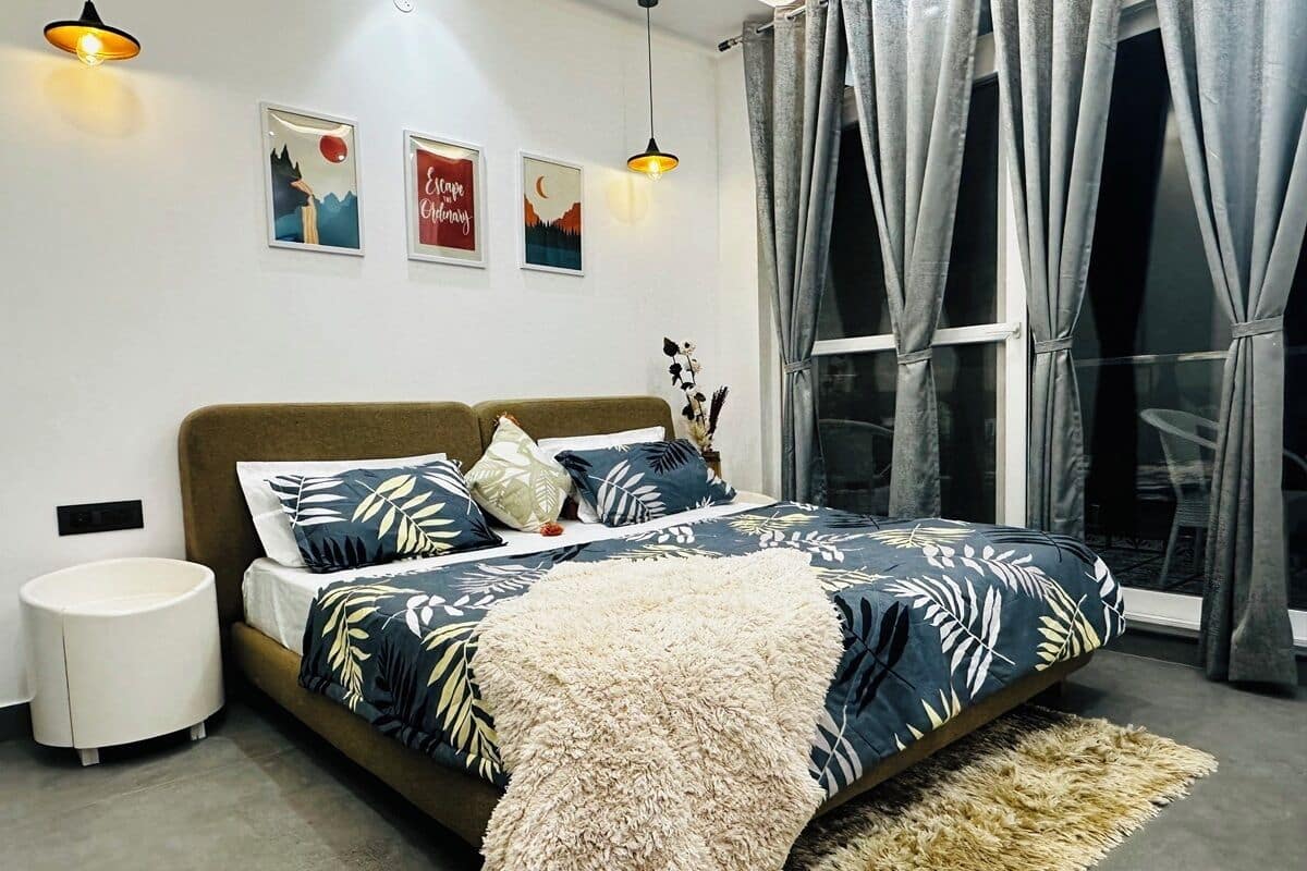 A bedroom with a bed, bedside tables, a window with curtains, and wall art.