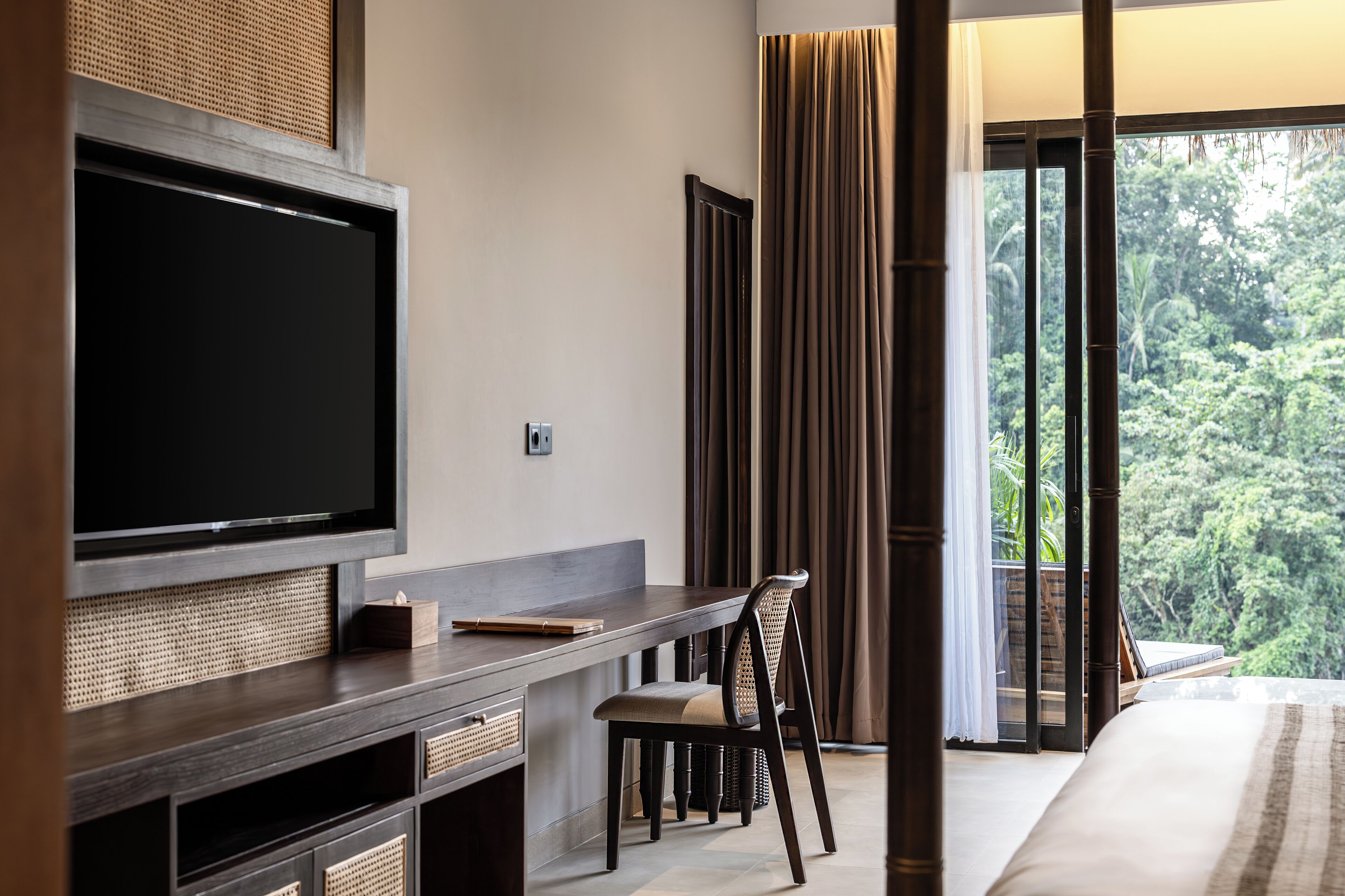 Una habitación de hotel moderna con una televisión de pantalla plana grande, un escritorio de madera, una silla cómoda y una cama.