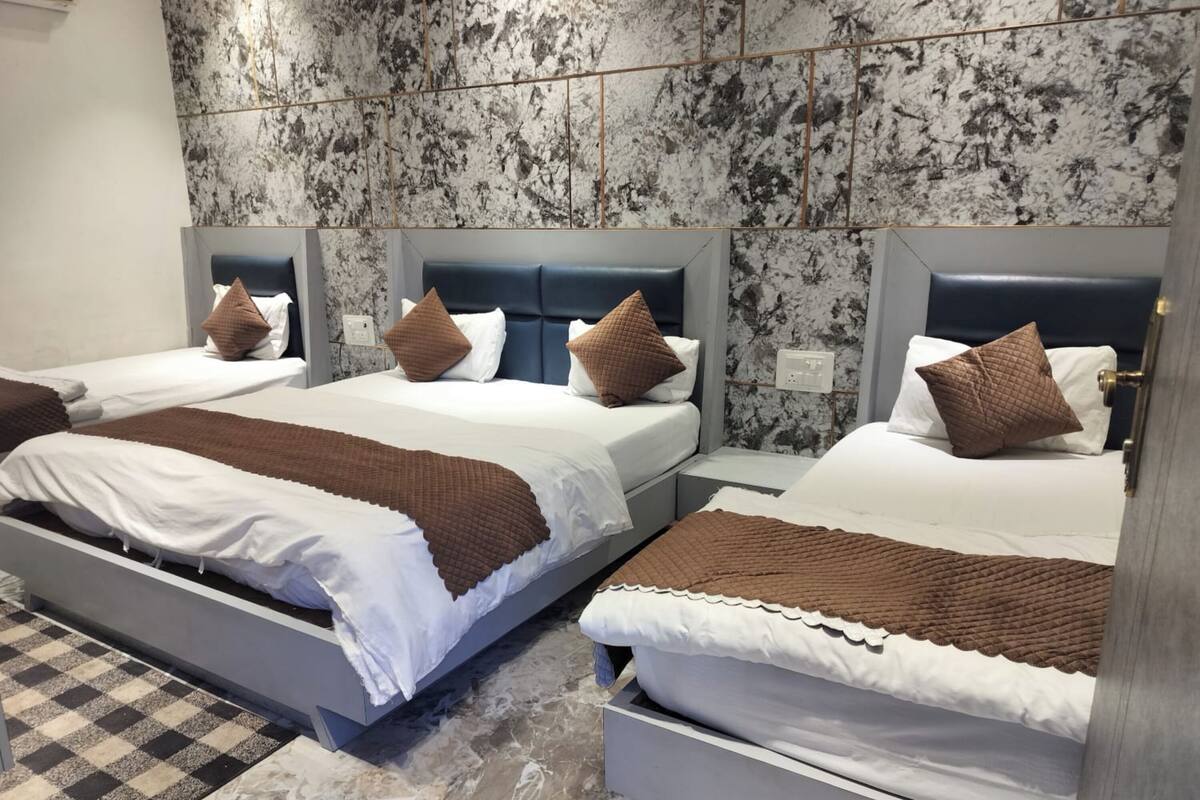 Habitación de hotel con dos camas, suelo de mármol y alfombra a cuadros.
