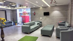 A modern living room with grey sofas, a green ottoman, and a small green rug. - ShrI Balaji Dham (Vrindavan)