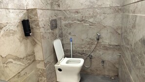 A small, marble-floored bathroom with a toilet, a hand dryer, and a shower. - ShrI Balaji Dham (Vrindavan)