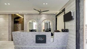 A reception area with a marble counter, a ceiling fan, and a sign that reads "Collection." - ShrI Balaji Dham (Vrindavan)