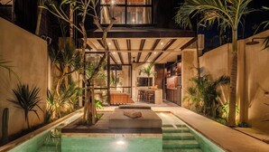 Un espace piscine intérieur moderne comprenant un salon, un bar et une cuisine.