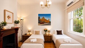 A hotel room with two beds, a fireplace, a chandelier, a painting, and a window with a view. - Rare 3 Parking! Amazing City Views, CBD at Doorsteps, 3BR2B Beautiful Terrace (West Melbourne)