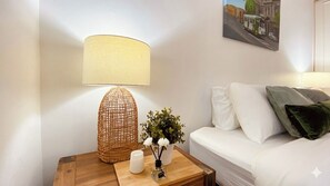 A neatly arranged room with a white sofa, a wooden nightstand with a lamp, a candle, and a small potted plant. - Rare 3 Parking! Amazing City Views, CBD at Doorsteps, 3BR2B Beautiful Terrace (West Melbourne)