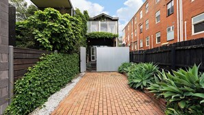 A narrow brick pathway flanked by dense green foliage and a brick building with multiple windows. - Rare 3 Parking! Amazing City Views, CBD at Doorsteps, 3BR2B Beautiful Terrace (West Melbourne)