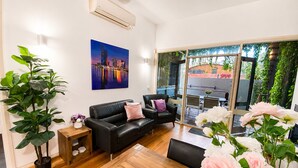 A modern living room with a black leather sofa, a wooden coffee table, and a large window with a view of a cityscape. - Rare 3 Parking! Amazing City Views, CBD at Doorsteps, 3BR2B Beautiful Terrace (West Melbourne)