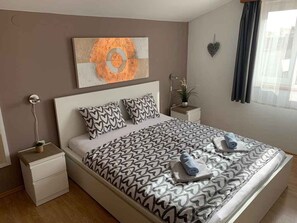 A neatly made bed with patterned bedding, a bedside table with a lamp, and a wall-mounted artwork. - Holiday apartment with air conditioning near the beach (Medulin)