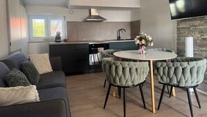 Cocina moderna con comedor, sofá y televisión.