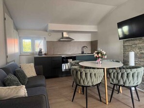 A modern kitchen with a dining area, a sofa, and a TV. - Holiday apartment with air conditioning near the beach (Medulin)