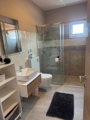 A modern bathroom with a glass shower enclosure, a white sink, and a toilet. - Holiday apartment with air conditioning near the beach (Medulin)