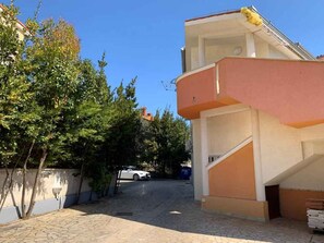 A building with a curved facade, a staircase, and a paved courtyard. - Holiday apartment with air conditioning near the beach (Medulin)