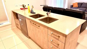 Een moderne keuken met twee spoelbakken, een vaatwasser en houten kastjes.