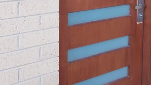 Une porte en bois, dotée de traverses horizontales, et un clavier de sécurité fixé au mur à côté.