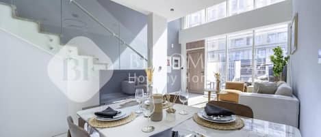 A modern dining area with a glass table, chairs, and a staircase.