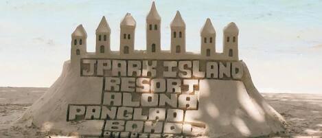 Un castillo de arena con la frase "SPARK ISLAND RESORT ALONG PANCLAD BEACH" escrita en él.