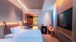 Quarto de hotel com uma cama grande, uma mesa de trabalho com cadeira, televisão e banheiro com espelho.