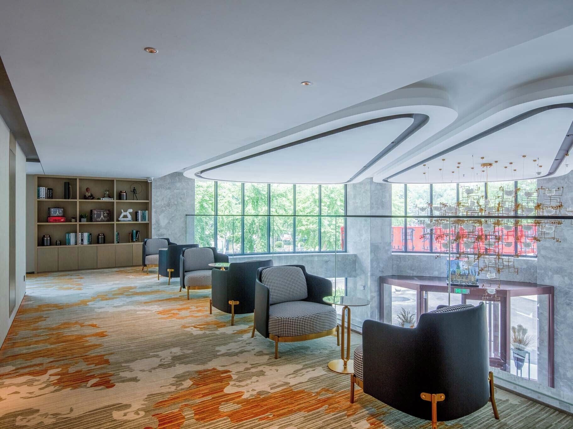 A modern interior with a large window, a bookshelf, and a patterned carpet.