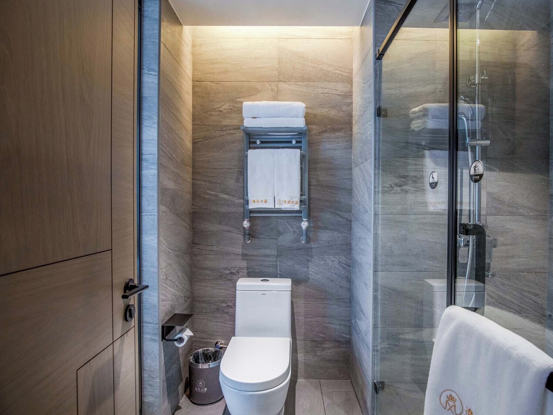 Un baño moderno con inodoro, toallero y cabina de ducha con paredes de vidrio.