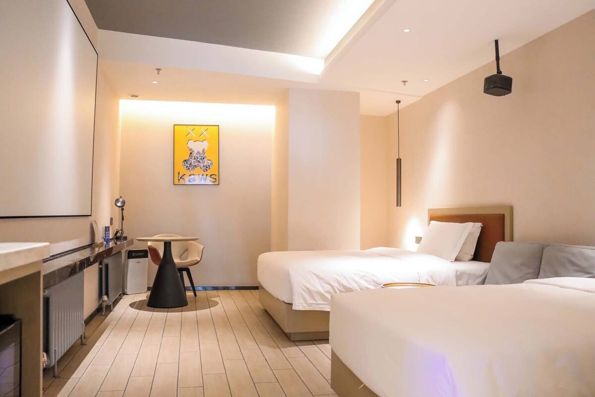 A hotel room with two beds, a small table, and a chair.
