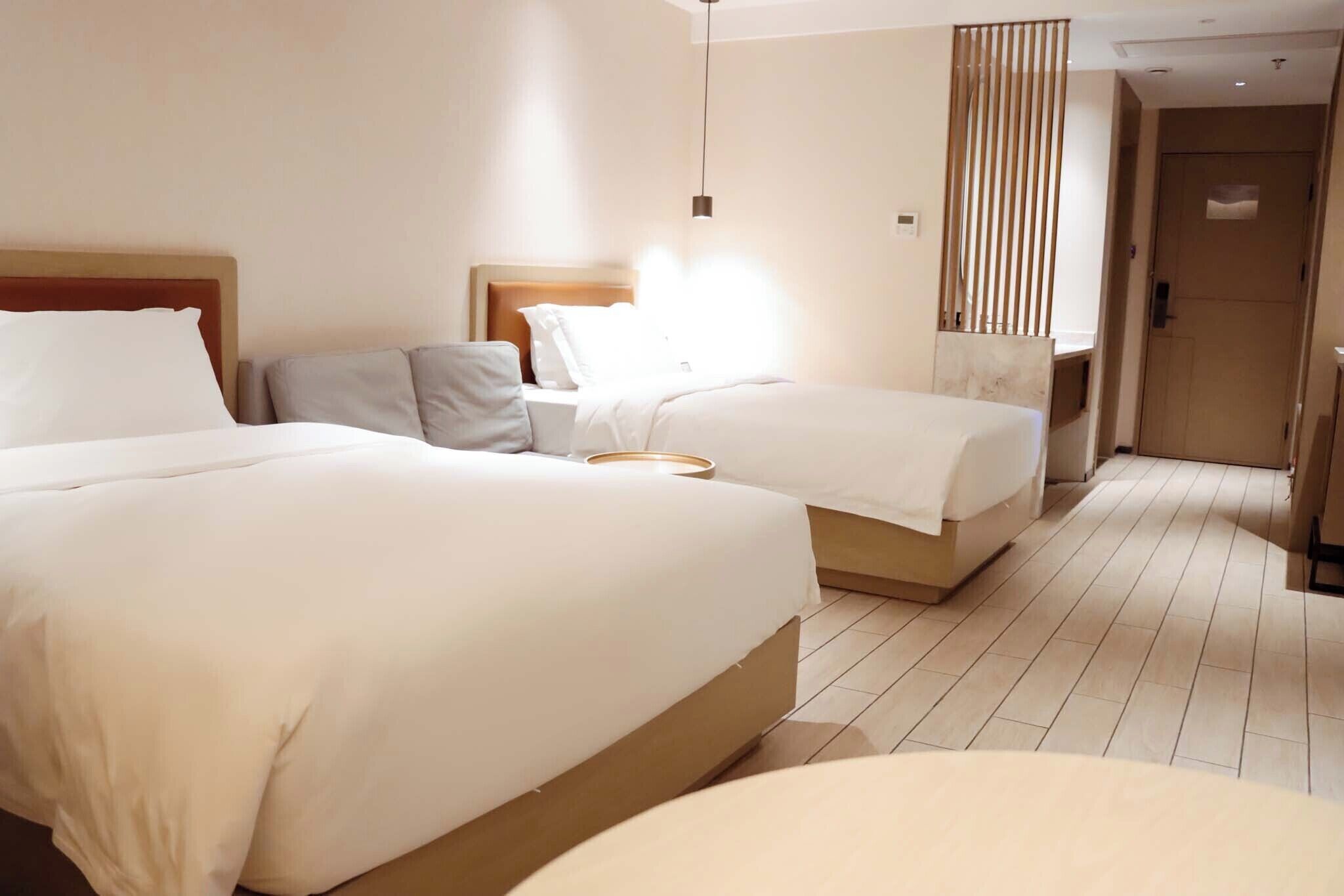 Une chambre d’hôtel avec deux lits, une table de chevet, une lampe et une porte.