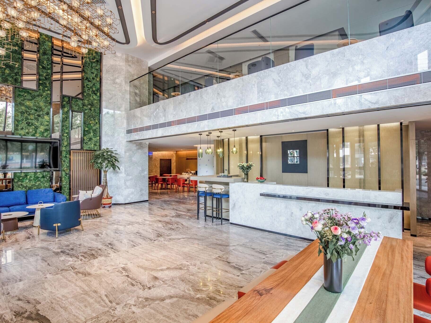 A spacious lobby with a marble floor, a reception desk, and a seating area with a blue sofa and chairs.