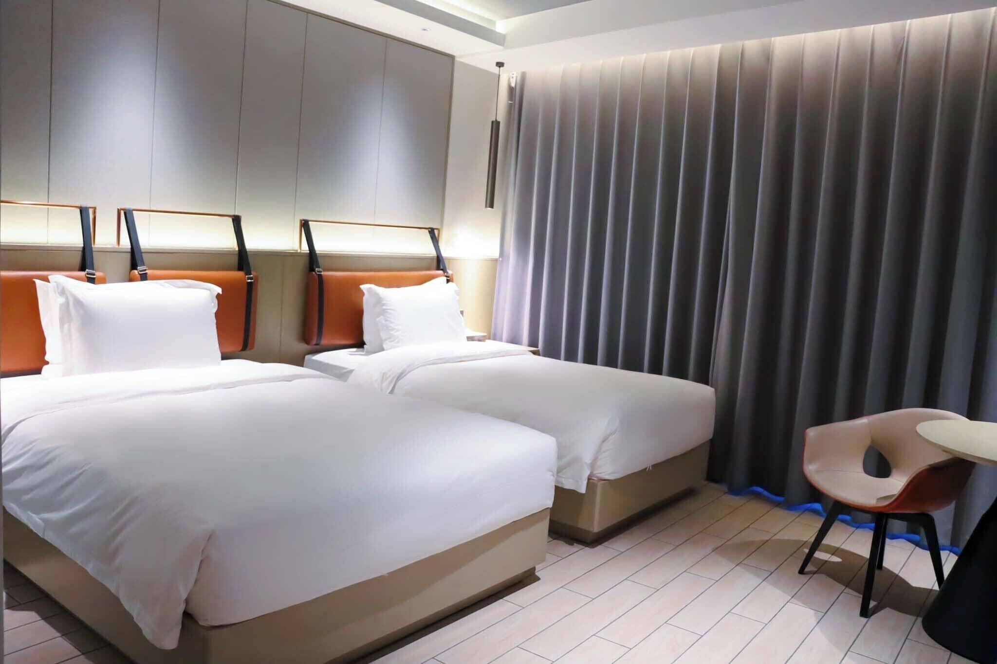 A hotel room with two beds, a desk, and a chair.
