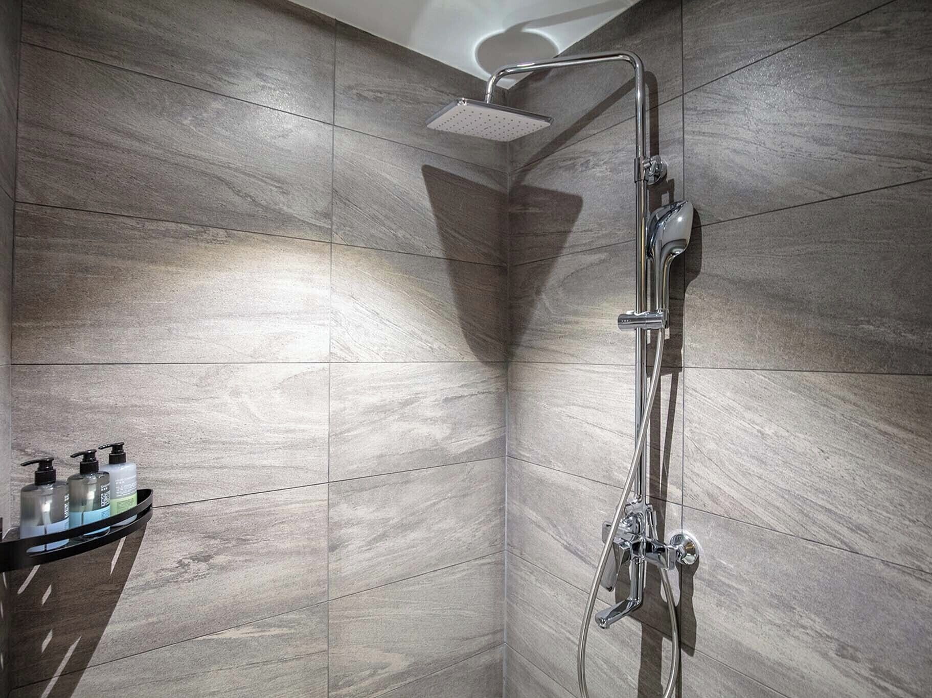 A modern shower with a handheld showerhead and a wall-mounted faucet.