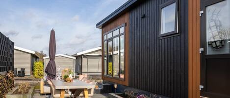 A modern house with a patio, outdoor furniture, and a garden.