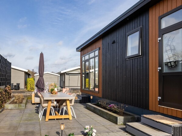 A modern house with a patio, outdoor furniture, and a garden.