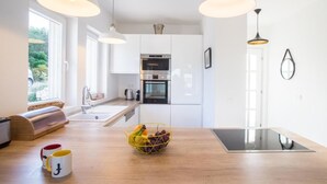 A modern kitchen with white cabinets, a wooden countertop, and pendant lighting.