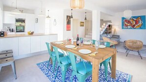 A modern kitchen with white cabinets, a wooden dining table, and teal chairs.