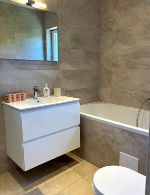 A modern bathroom with a white vanity, a bathtub, and a toilet. - Villa Lastavica - swimming pool - large garden - walking distance to the beach (Vis)